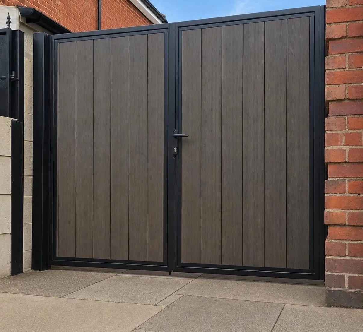 Dark steel double gate with composite panel infill between brick walls