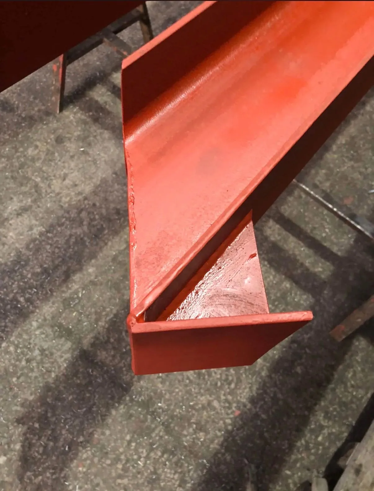 Close-up of a red-oxide coated structural steel beam end and welded connection
