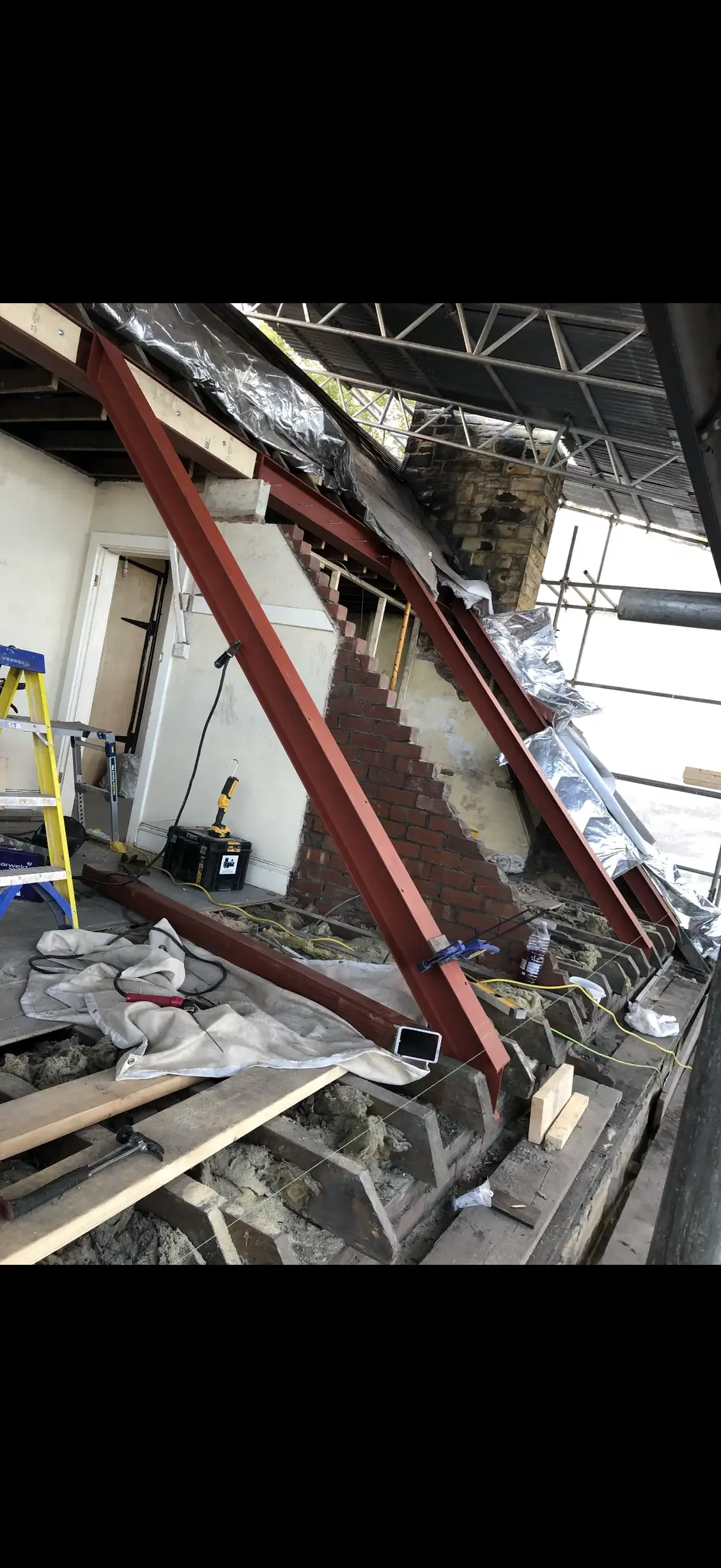 Red-oxide coated structural steel beams installed beside a masonry stairwell during renovation